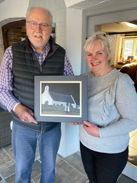 Carys James, Stepside Agriculture Contractors, Gwbert Road, Cardigan with her new purchase of an original painting of Mwnt Church by Ceredigion artist Wynne Melville Jones,