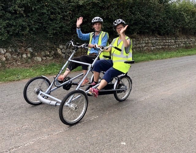 Gilly demonstrates the club’s pedal assisted electric side-by-side bicycle during a bicycle ride with daughter Cara