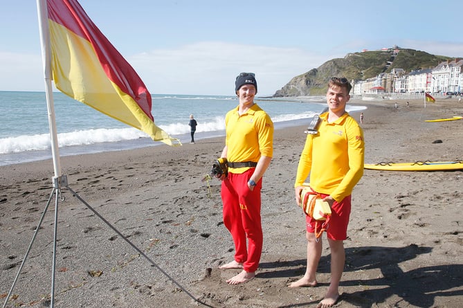 AB3005 RNLI198 PHOTO CODE 19DPJ30MAY198 - PHOTO DAVID ARWYN PARRY JONES / CAMBRIAN NEWS PRESS PHOTOGRAPHER - 30MAY2019 - REF Simon; RNLI lifeguards have returned to their posts across Wales from Saturday (25 May) to offer safety advice and assistance over the May half term. The charityâs lifeguards will be on the following beaches to welcome those enjoying the half term holidays on the Welsh coast: CeredigionÂ - Borth, Aberystwyth North, Llangrannog, New Quay Harbour, Aberporth. A lifeguarding service will be provided everyday between 10am-6pm over the school half term. The lifeguardâs role is to advise, supervise and rescue those in trouble on the beach or in the water. - PHOTO - Lifeguards Ellis Evans and Huw Jenkins at North Beach Aberystwyth Prom last Sunday. 