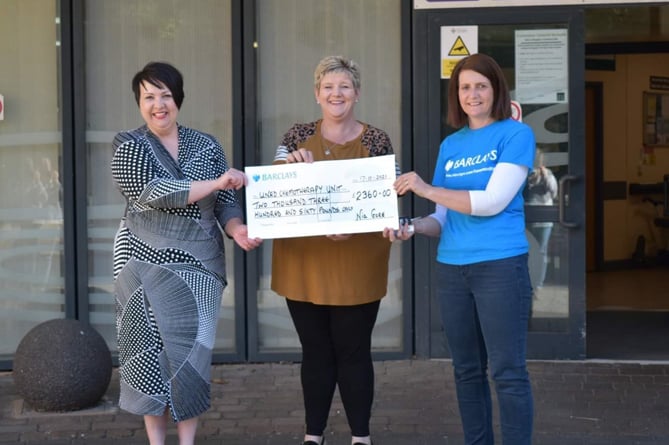 Nia Gore hands over a cheque to Dr Elin Jones and Meinir Chambers, from Barclays Bank, who match funded whatever was raised