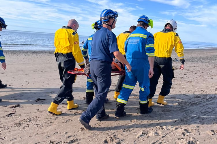 New Quay RNLI and New Quay Coastguard teams carry the casualty off the beach