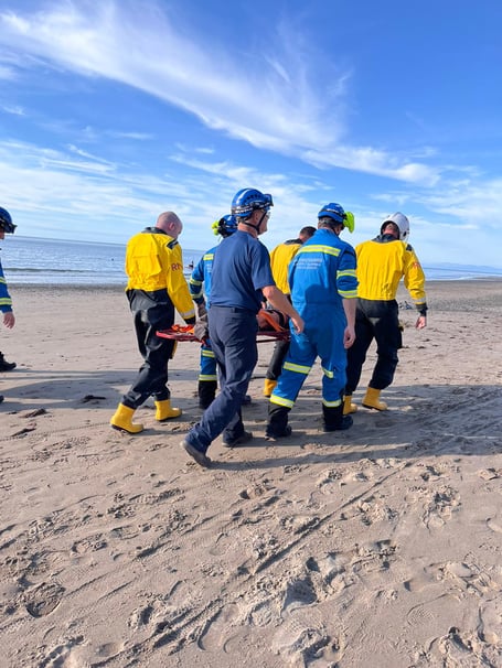 New Quay RNLI and New Quay Coastguard teams carry the casualty off the beach