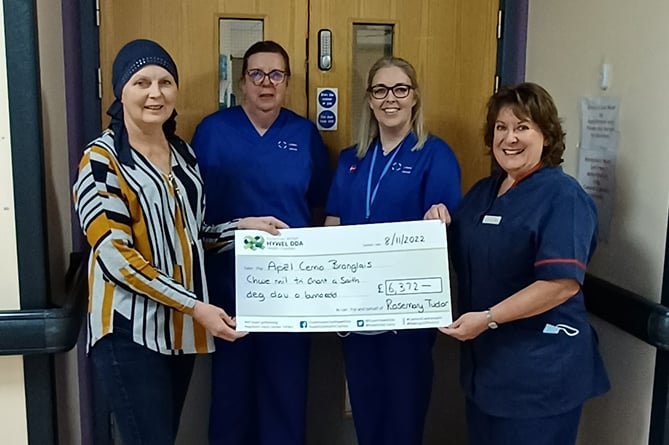 Rosemary Tudor handing over a cheque to oncology clinical nurse specialist Rhian Jones and haematology clinical nurse specialists Heulwen Lewis and Eirian Gravell