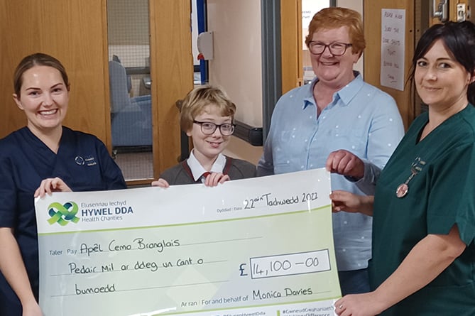 Monica (second from right) with her niece Dilwen Davies (second from left) handing over a cheque for £14,100 to chemotherapy sister Cassie Thomas and healthcare support worker Rebecca Fletcher