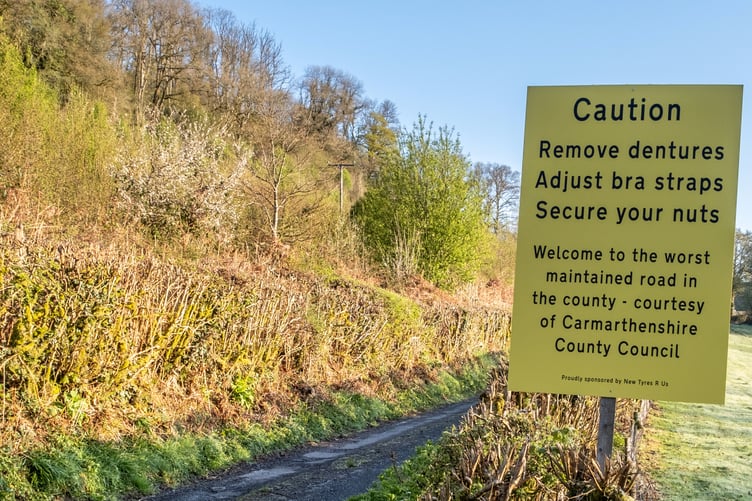 The sign near the Abergorlech Road in Carmarthenshire in Wales. See SWNS story SWLNpothole. Residents fed-up with potholes have installed a fake road sign warning drivers to 'adjust bra straps', 'remove dentures' and 'secure their nuts'. Locals led by John Burton, 68, stuck up the hilarious sign claiming they are being 'ignored' by the council.The sign was put up yesterday (26/4) near the Abergorlech Road in Carmarthenshire in Wales.It says: "Caution. Remove dentures. Adjust bra straps. Secure your nuts.