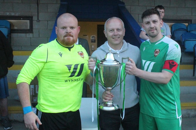 Llansantffraid captain Khyam Wyton and goalkeeper Dave Jones receive the trophy from former Caersws legend Graham Evans