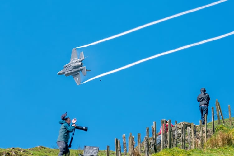 Heart-stopping picture taken by Tom Pennington shows plane spotter's hat getting blown off his head as fighter jet roars overhead. See SWNS story SWSMjet. This is the moment a plane spotter missed his shot when his hat was blown off by a low-flying F-35 fighter jet. Tom Pennington, 50, captured the hilarious âone-in-a-millionâ snap while photographing the RAFâs low-level training exercise in North Wales. The F-35 â which has a dizzying top speed of 1,200mph â roared overheard taking a group of plane spotters by surprise. Ambulance technician Tom pictured the scene during the military exercise on May 12.