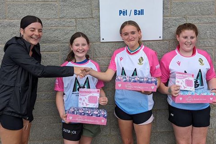 Lleucu, Nia and Gwen receiving period products from Lowri Evans ofGwasaneth Ieuenctid Ceredigion