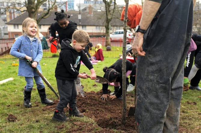 Children bedding in a newly planted apple tree