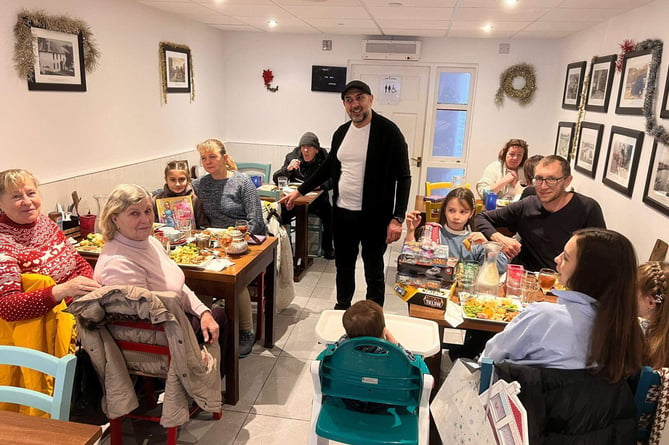 Ahmet Acikel in his Home Cafe on Christmas Day with attendees of his free Christmas dinner
