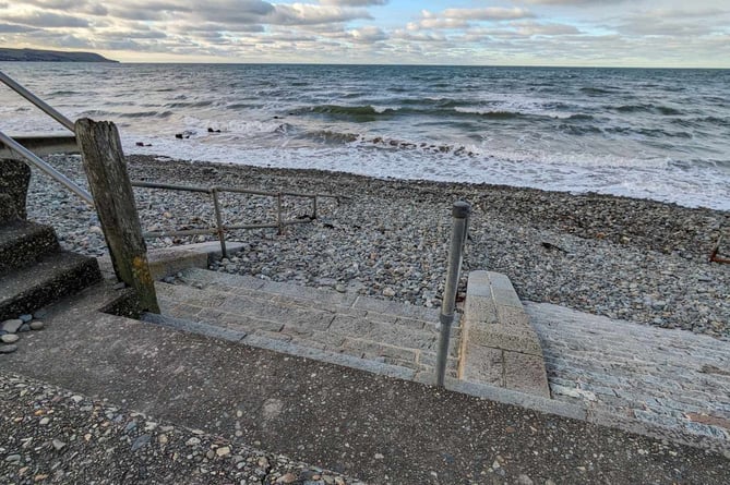Sand and stones pile high covering handrails and restricting access to the beach