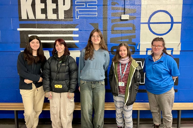 Coleg Menai art students in front of the mural they painted in the home dressing room at Nantporth Stadium