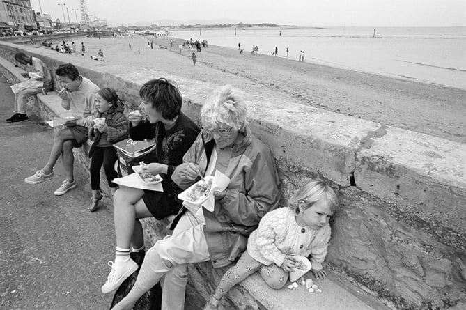 Family eating by the sea while on holiday, Rhyl, Wales