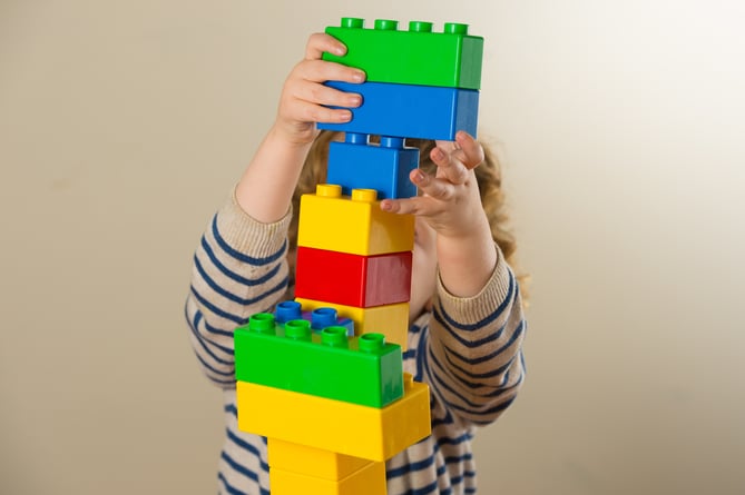 A preschool age child plays with plastic building blocks