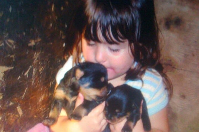 Sarah as a child, with a litter of rottweiler puppies