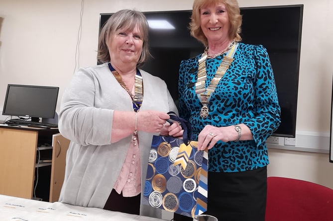 President Sian presenting District Chairman Muriel McGrath with a cheque from Tywyn Inner Wheel for £100 for her chosen charity which this year is Cerebral Palsy, and a book on Tywyn by Jean Napier