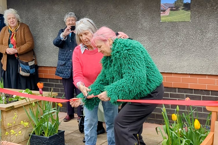 MP Liz Saville Roberts cuts the ribbon of the new garden at Llys Cadfan, assisted by resident Pat Flippence