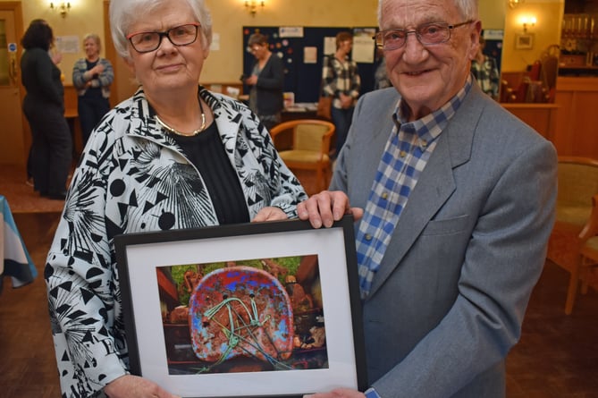 Dr Alan Axford receives a specially commissioned photograph by Marian Delyth from incoming chair Gwerfyl Pierce Jones