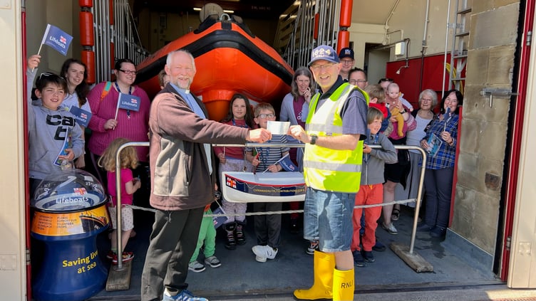 Penrhyndeudraeth’s Holy Trinity Church Saturday Club members donate £70 to the RNLI. Reverend Roland Barnes is pictured here presenting a cheque to Archdeacon Robert Townsend, who is also a RNLI Lifeboat volunteer at Criccieth Lifeboat Station.