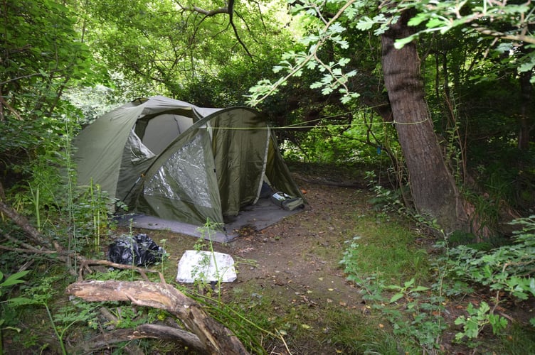 A tent in  bushes hidden by the banks of the Ystwyth river in Aberystwyth