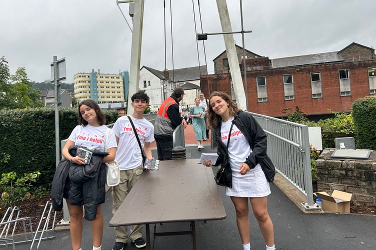 Three friends from Patagonia, Meleri Pinciroli, 18, Kiara Ace, and Santiago Pires, both 17 years old, greeted visitors as they walked over the bridge from Pontypridd to the Maes in Parc Ynysangharad.