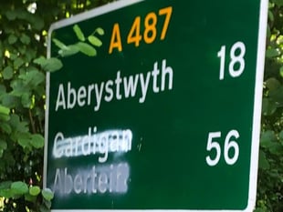 Vandals graffiti over Welsh and English place sign for Aberteifi