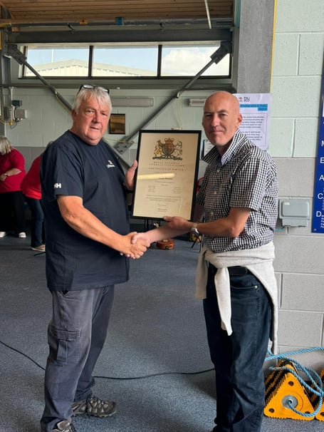 Jason Warren receives his certificate from Gerallt Williams, Pwllheli RNLI’s chair. Photo: RNLI/Caroline Jones