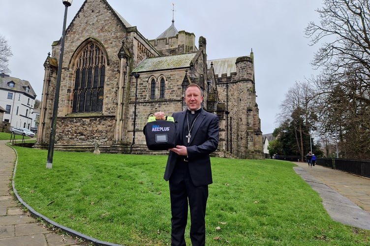 Bishop David is pictured holding a defibrillator at Bangor Cathedral