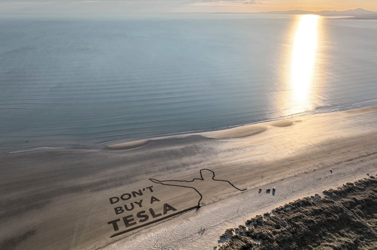 A Tesla driver has staged the "world's biggest anti-Elon Musk protest - a 250m long "Don't buy a Tesla" message raked into sand. Photo released March 18 2025. The driver, named only as Prama, carved out the words - alongside a silhouette of Musk's now infamous 'salute' he gave at an inaugural event in Washington, DC. British political campaign group Led By Donkeys staged the protest on Black Rock Sands - Traeth y Greigddu - near Porthmadog, Wales. It was made by attaching a huge rake to the back of a Tesla Model 3, which was driven around the beach to create the 250m x 150m message.