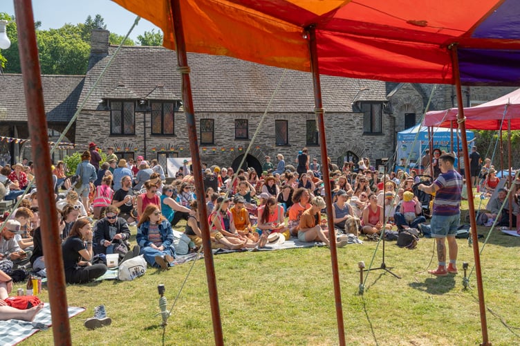 Poet Kaan K reading to a full audience on the picnic stage at this year's Machynlleth Pride, hosted at the Owain Glyndŵr Centre
