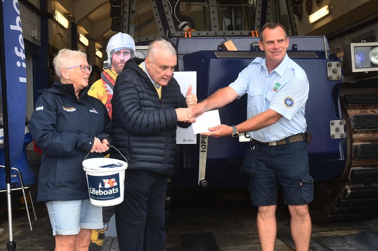 Alun Williams presenting a cheque for £650 to Aberdyfi RNLI senior Helm Will Stockford. Photo: Doris O'Keefe