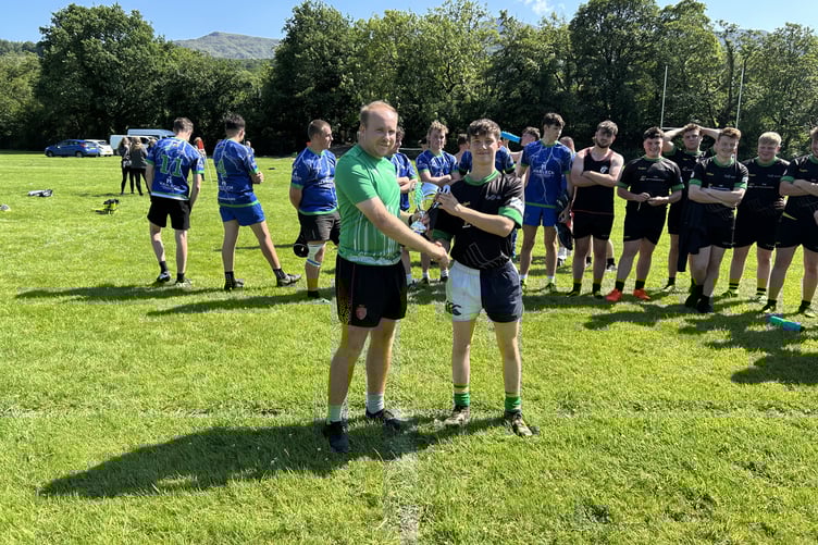 WRU / Grŵp Llandrillo Menai rugby engagement officer Ollie Coles presenting the North Wales Cup to Huw Watkins, captain of Glynllifon’s rugby team