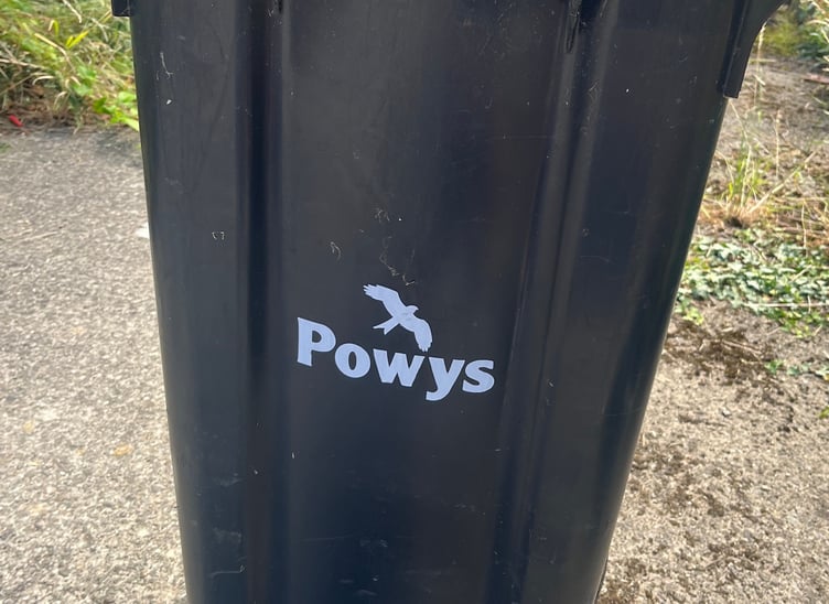 A black residual waste bin in Powys