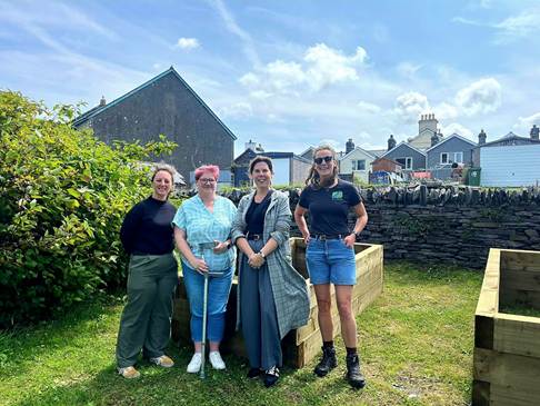 Cllr Menna Trenholme (deputy Gwynedd Council leader), Cllr Meryl Roberts, Penrhyndeudraeth Ward, Cllr Nia Jeffreys (Gwynedd Council leader) with Lauren Quaeck, Y Dref Werdd at the Millennium Park with the raised bed boxes