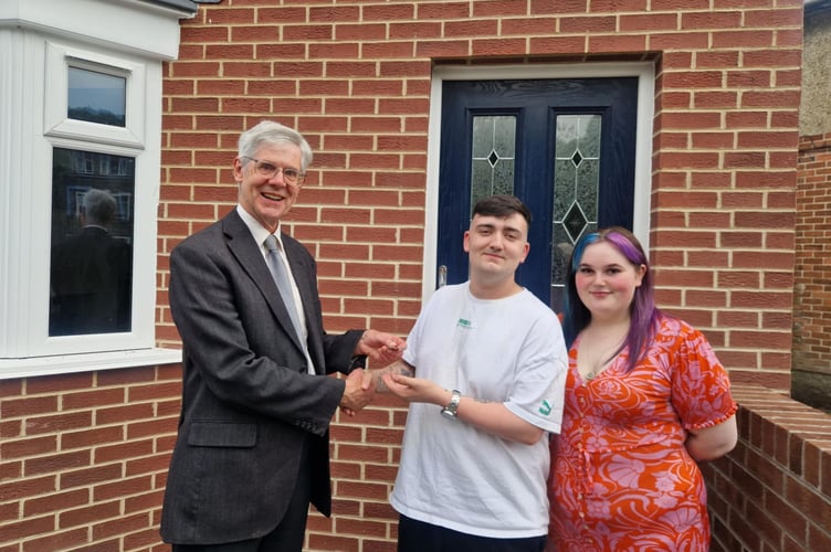 Cllr Paul Rowlinson, Gwynedd Housing and Property Cabinet Member, handing the keys over to Ffion and Rhodri's new home. Photo: Gwynedd Council