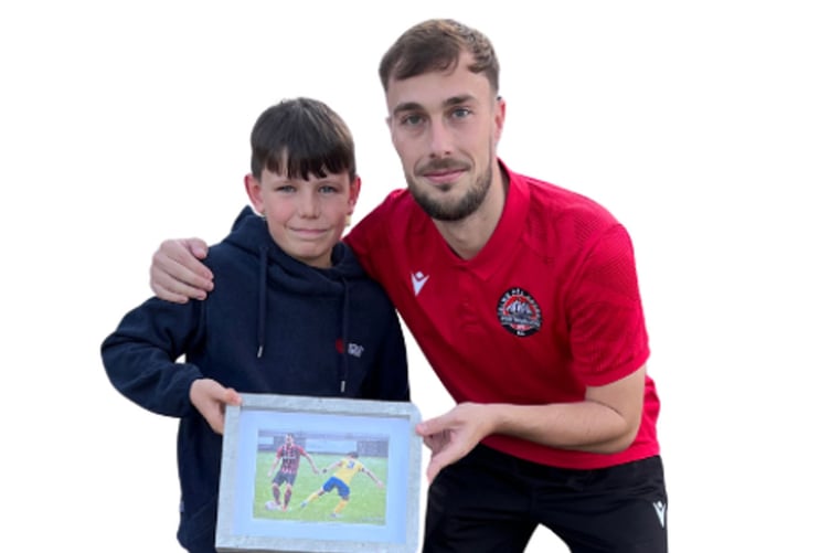 Porthmadog's Shaun Cavanagh has been named Player of the Month for September, as voted by the supporters. He received a commemorative plaque from Port TV, refreshing beer courtesy of Purple Moose Brewery, and a framed photograph by Jeff Guile. The picture was presented to Shaun by Jack Wyn Guile, Jeff’s grandson, following the match against Llannefydd