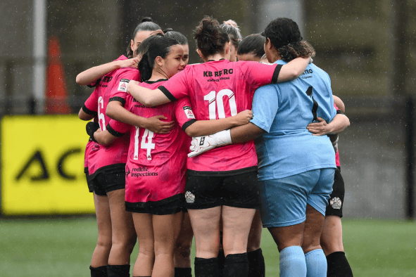 Aberystwyth Town Women’s huddle in their pink away kit before kick-off (Credit: FAW/Craig Thomas)
