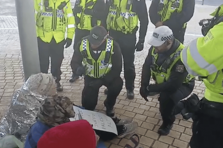 An elderly woman before she was taken to a police van. Her sign reads: 'I oppose genocide. I support Palestine Action'. Photo: Anonymous