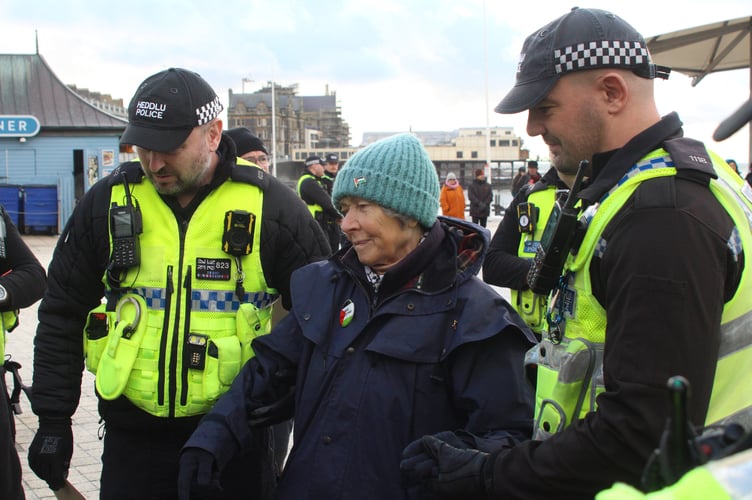 Elizabeth Morley, 80, being helped into a police van by two officers at a Palestine Action protest on 18 November on Aberystwyth Promenade. Photo: Palestine Solidarity Aberystwyth