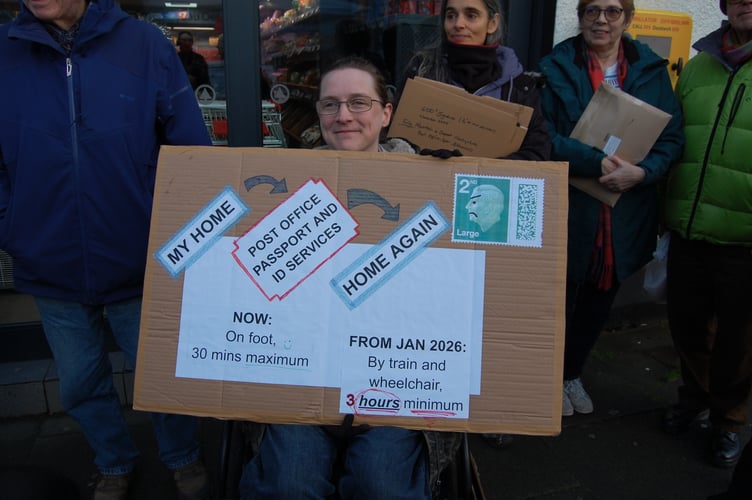 Cassian Lodge holding their sign outside the Post Office in Machynlleth, as staff meet with senior management about proposals to downgrade the Post Office. Photo: The Cambrian News
