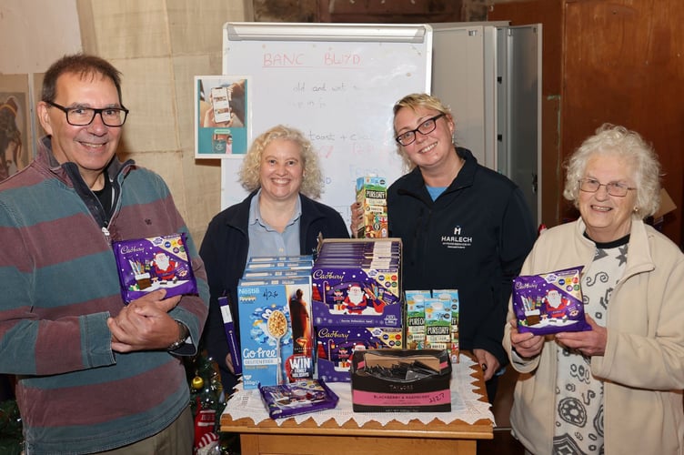 Harlech Foodservice staff Mel Amor, centre, left and Ursula Scurrah-Price, called in to Pwllheli Food Bank with a donation including seasonal treats, gratefully received by Food Bank Chair David Hill and volunteer Wendy Hildyard. Photo: Phil Blagg Photography.