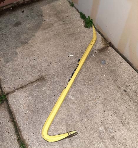 The front door was extensively damaged, and a yellow crowbar abandoned at the scene