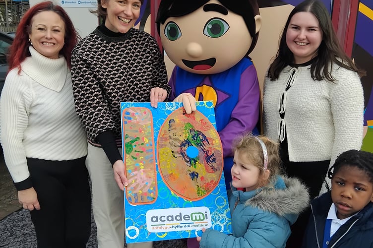 Academi Officers Annadele McDonagh. Ffion Davies, Seren Jenkins with Dewin and children from Camau Bach with a Birthday Card designed by Camau Bach and Cylch Meithrin Aberystwyth