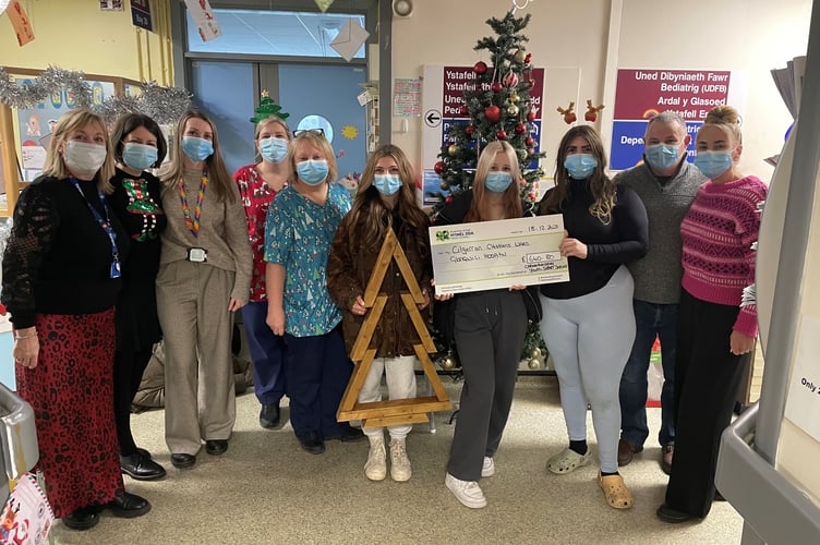 Children and young people from Carmarthenshire Youth Service present a cheque to Glangwili Hospital’s Cilgerran Ward