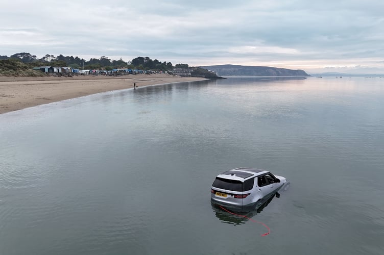 Video shows a car left on a beach submerged by the sea - and rowed over by paddleboarders. // Locals in the Welsh seaside village of Abersoch were left stunned after seeing the luxury 4x4 become fully engulfed  by the tide. Beach-goers spotted the Land Rover Discovery half-submerged in the water on Sunday  less than two miles away from Bear Grylls private island. The posh car, which sells for around £80,000 was spotted by one paddleboarder at around 7.30am, just over two hours before high tide.