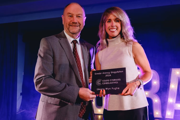 Lleucu Wyn Pughe presented with her award by Cefin Campbell, Minister for Skills and Tertiary Education, at the Coleg Cymraeg Cenedlaethol Awards. Photo: Y Coleg Cymraeg Cenedlaethol