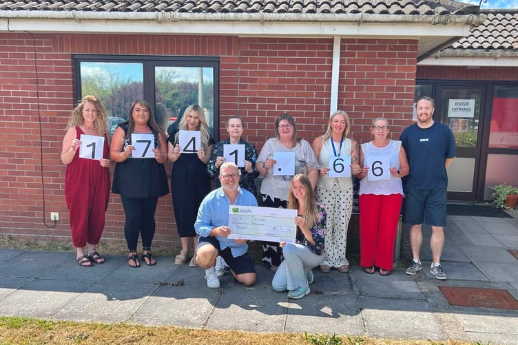 Morgan Thomas, Low Intensity Psychological Therapy Practitioner, and Andrew Homfray, Service Delivery Manager, holding cheque with the rest of the DBT team.